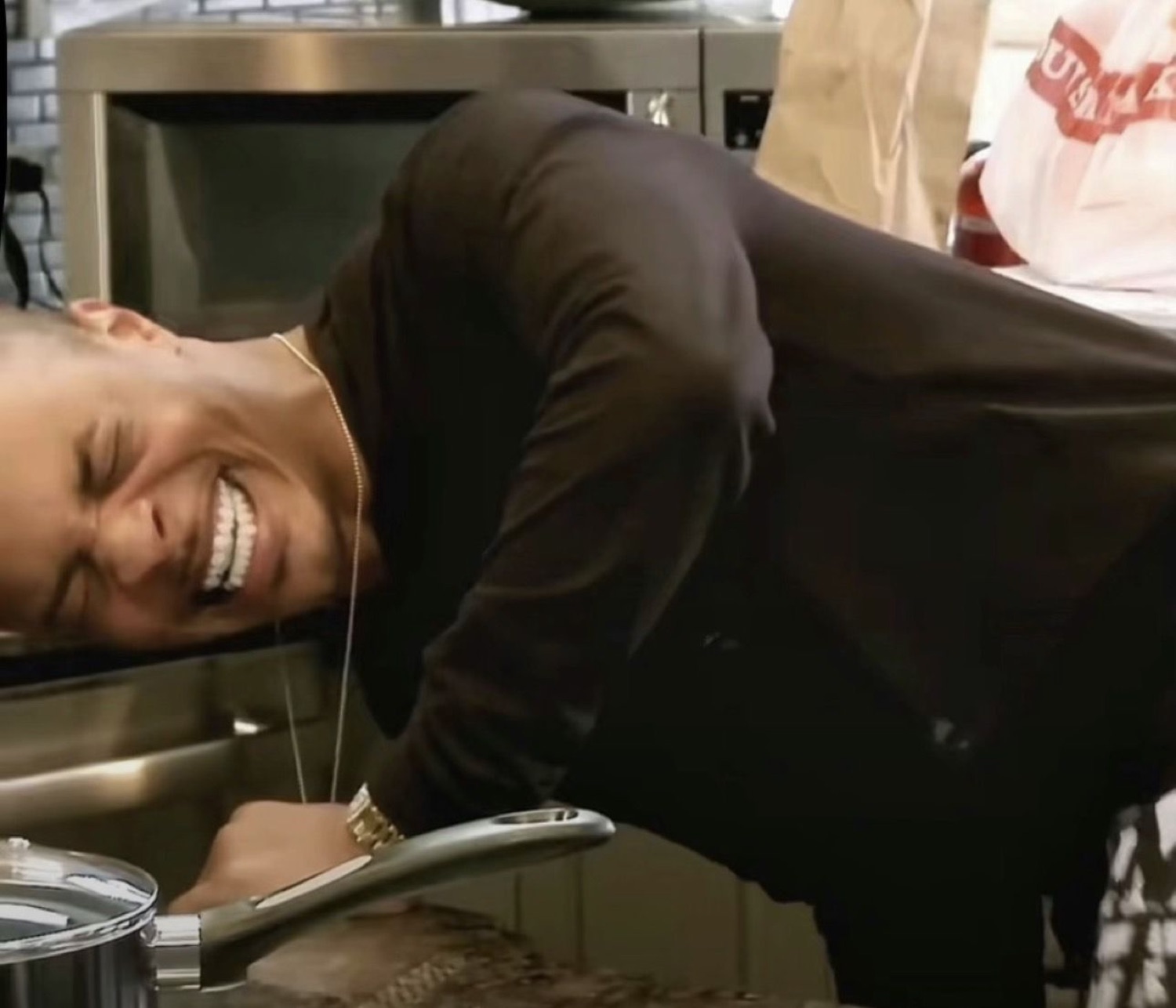 Man doubled over a counter cracking up, laughing so hard he's collapsing