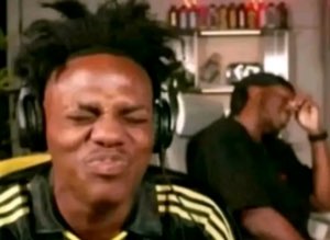 Man wearing headphones squeezing his eyes shut with a deep cringe-grimace face