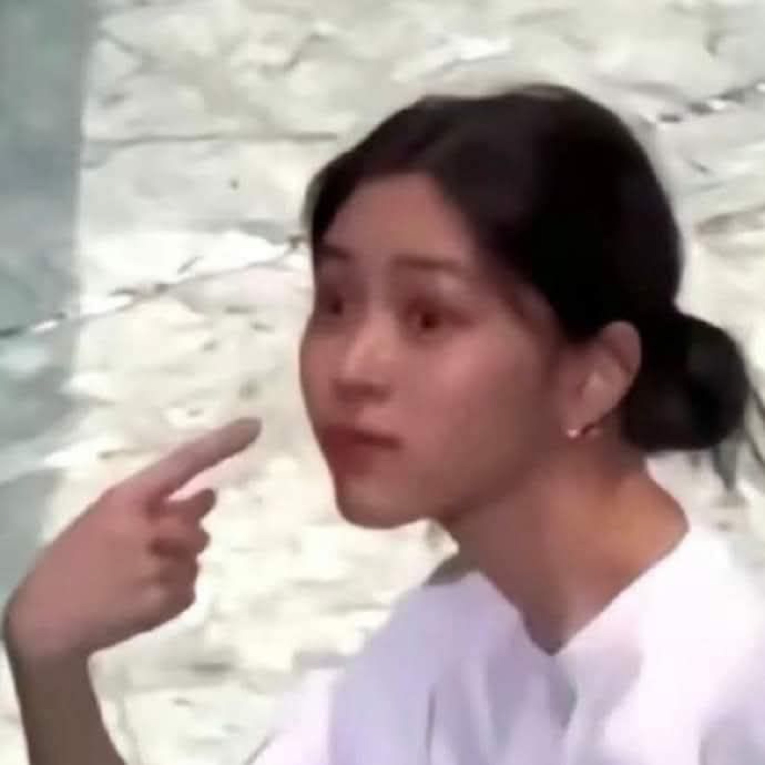Young woman being pointed at, staring off with a startled, bewildered expression