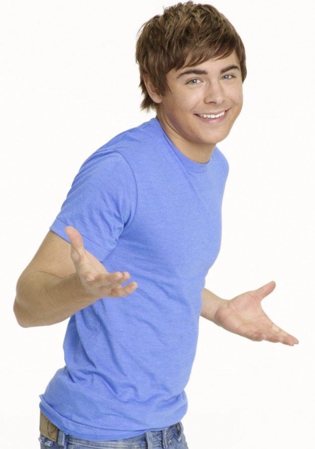 Young man in a blue tee grinning with both hands thrown out in a cheeky 'ta-da' pose