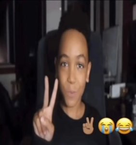 Young guy throwing up a peace sign with crying-laugh emojis on screen beside him