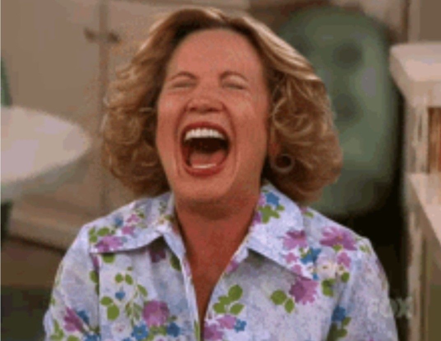 Woman in a floral blouse cackling with her head thrown back and mouth wide open