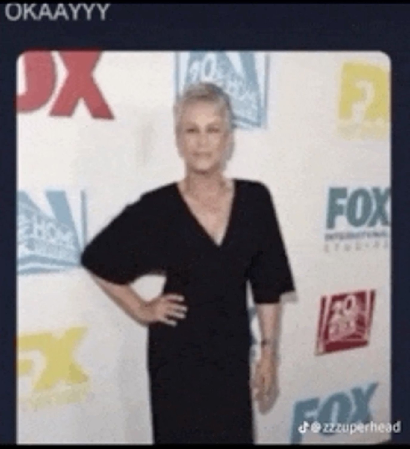 Jamie Lee Curtis posing with a hand on her hip at a Fox press wall, captioned 'OKAAYYY'