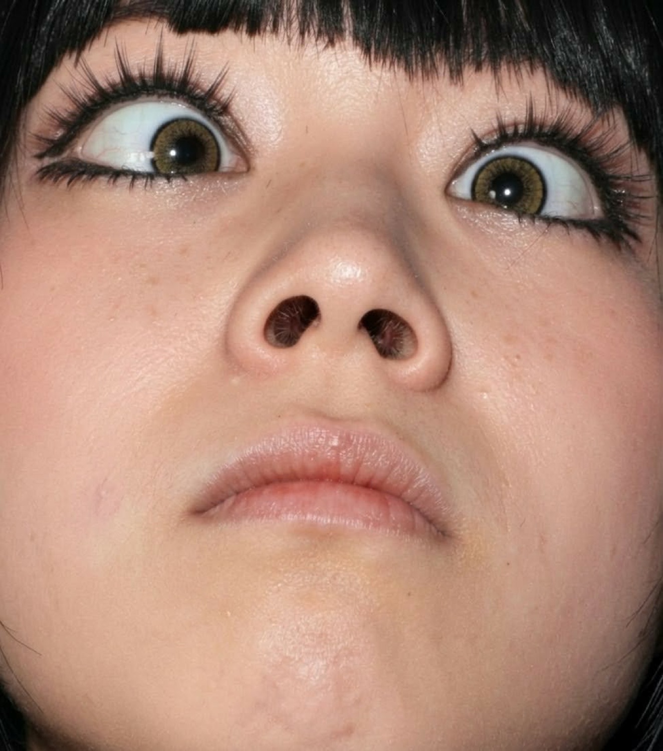 Woman with big anime-like eyes and bangs looking straight up, completely frozen in wide-eyed shock