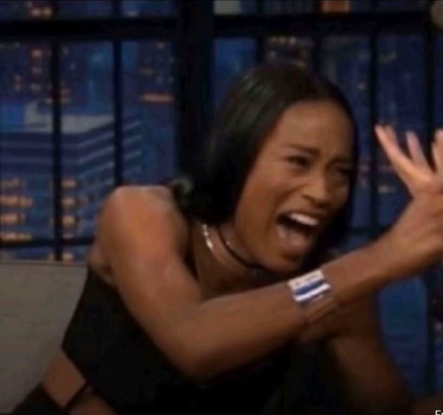 Woman on a late-night talk show set mid-scream, arms flung out in total panic