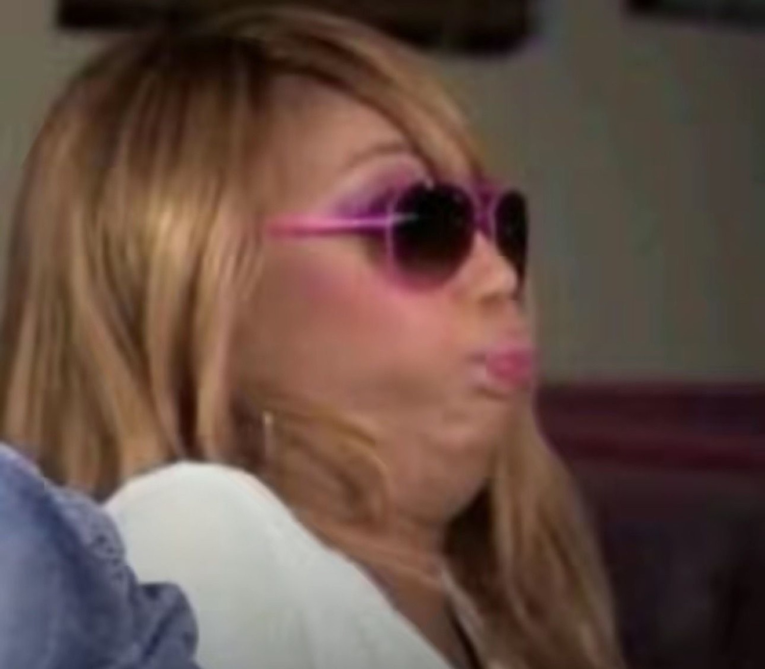 Woman in pink heart sunglasses puckering her lips with an unbothered, sassy vibe