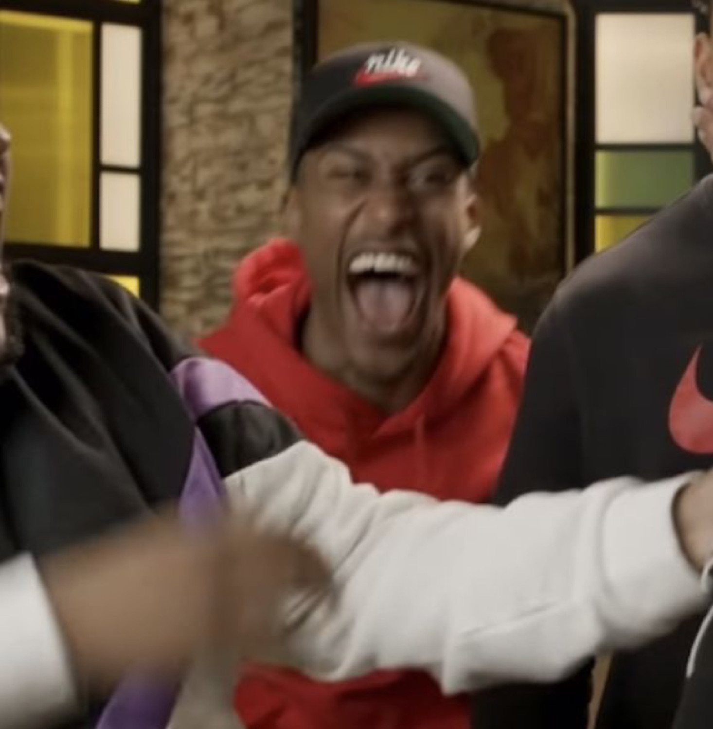 Guy in a red hoodie losing it with his mouth wide open and tongue out, laughing hysterically