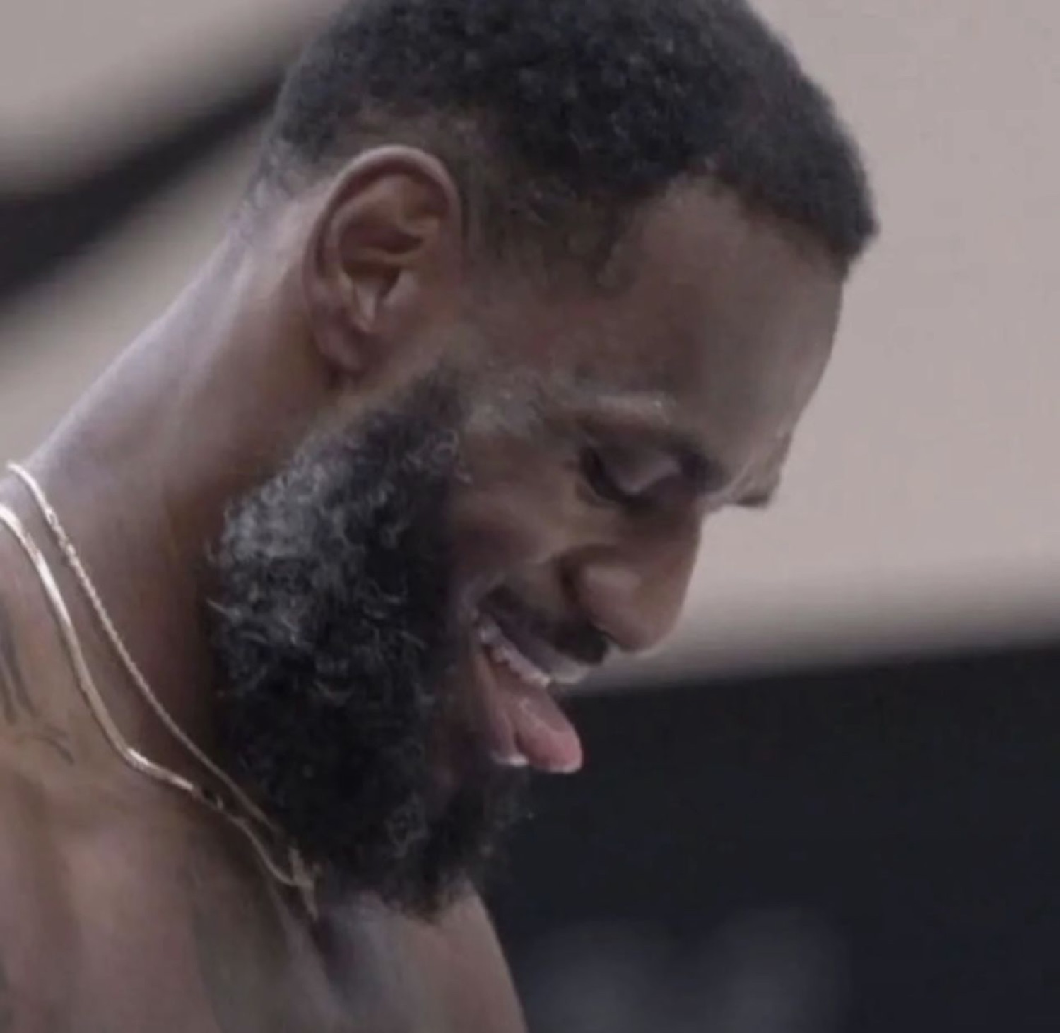 Bearded basketball player looking down and laughing to himself mid-game