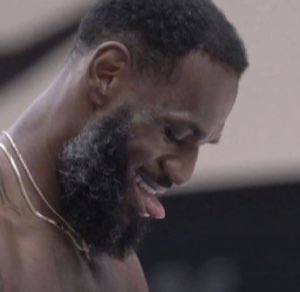 Bearded basketball player looking down and laughing to himself mid-game