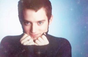 Man resting his chin on his fists with a dreamy, coy little smile amid sparkles