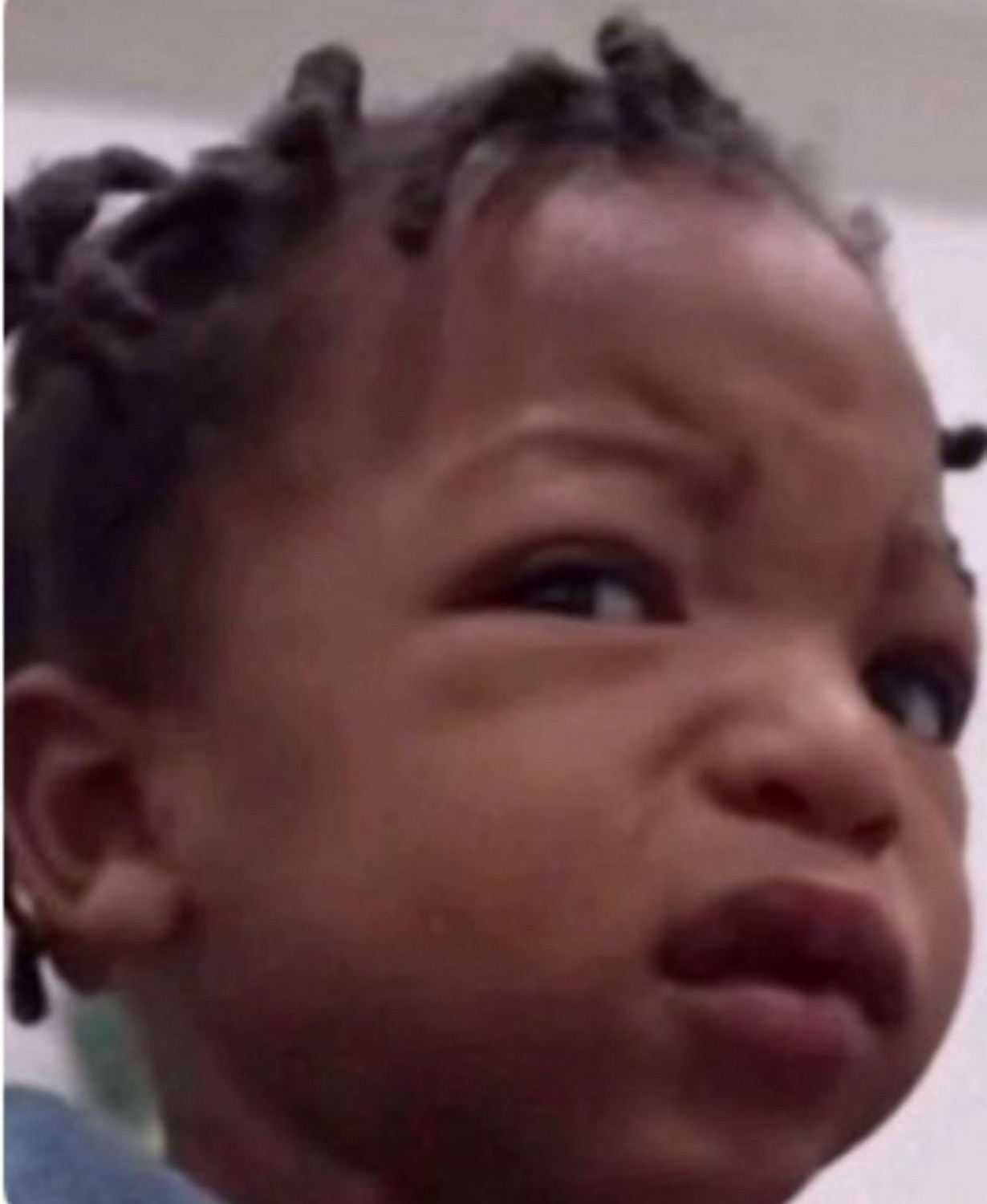Baby with braids scrunching up their face in a deeply unimpressed, judgmental glare