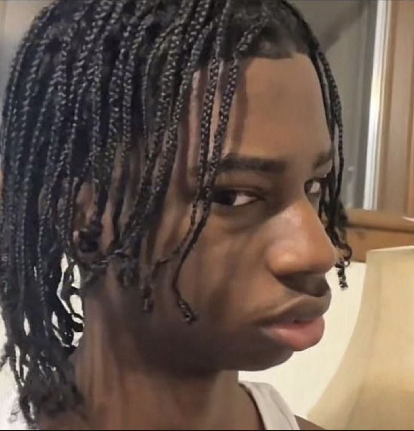 Guy with braids glancing sideways with a cool, unbothered side-eye