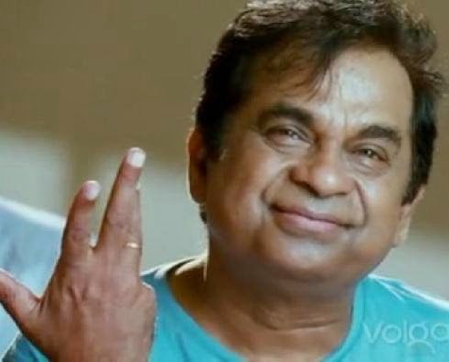 Brahmanandam smiling with two fingers raised