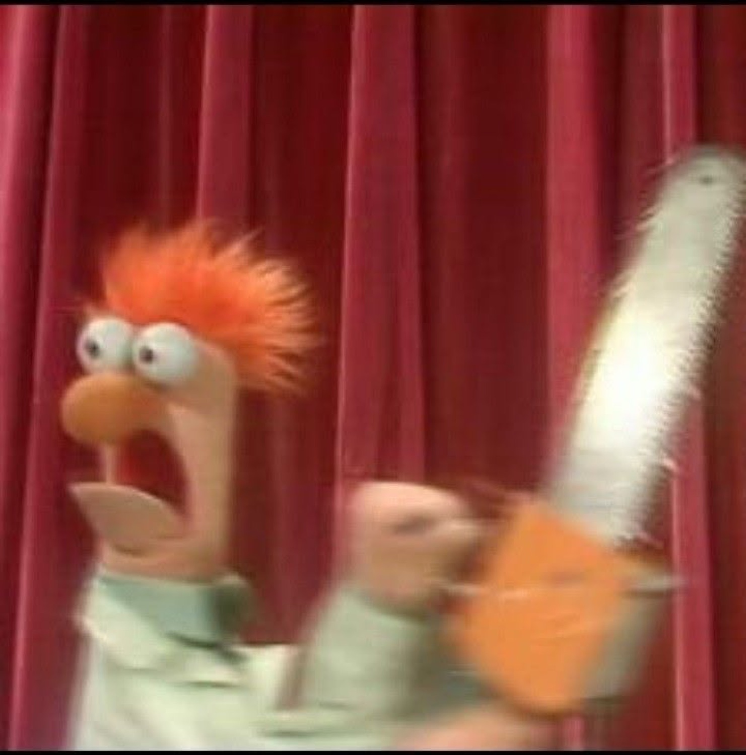 Beaker wide-eyed and shrieking as a chainsaw swings past the red curtain