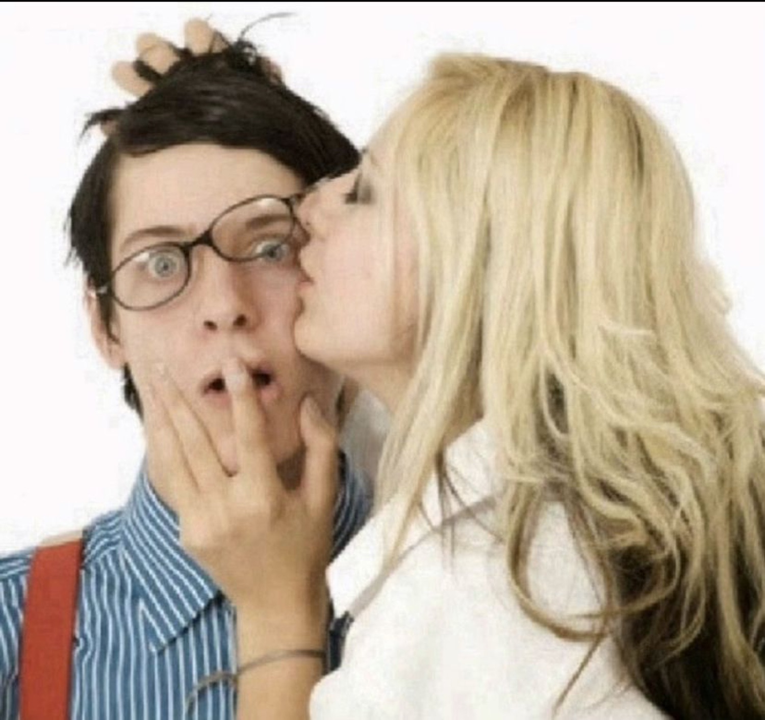 Wide-eyed guy in glasses looking completely shocked while a woman kisses his cheek