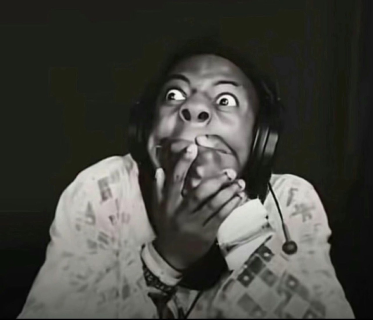 Streamer wearing headphones staring in wide-eyed terror at the screen, hands clasped near their face