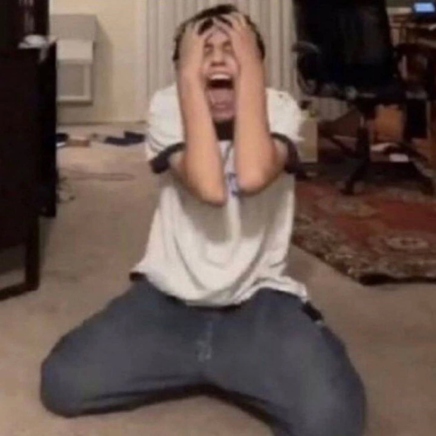 Man on his knees clutching his head and screaming in dramatic anguish