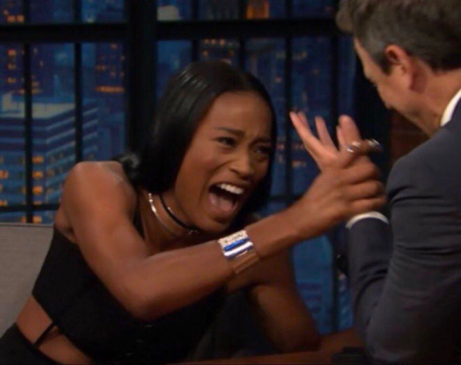 Woman on a talk show mouth wide open screaming with excitement and grabbing the host's hand