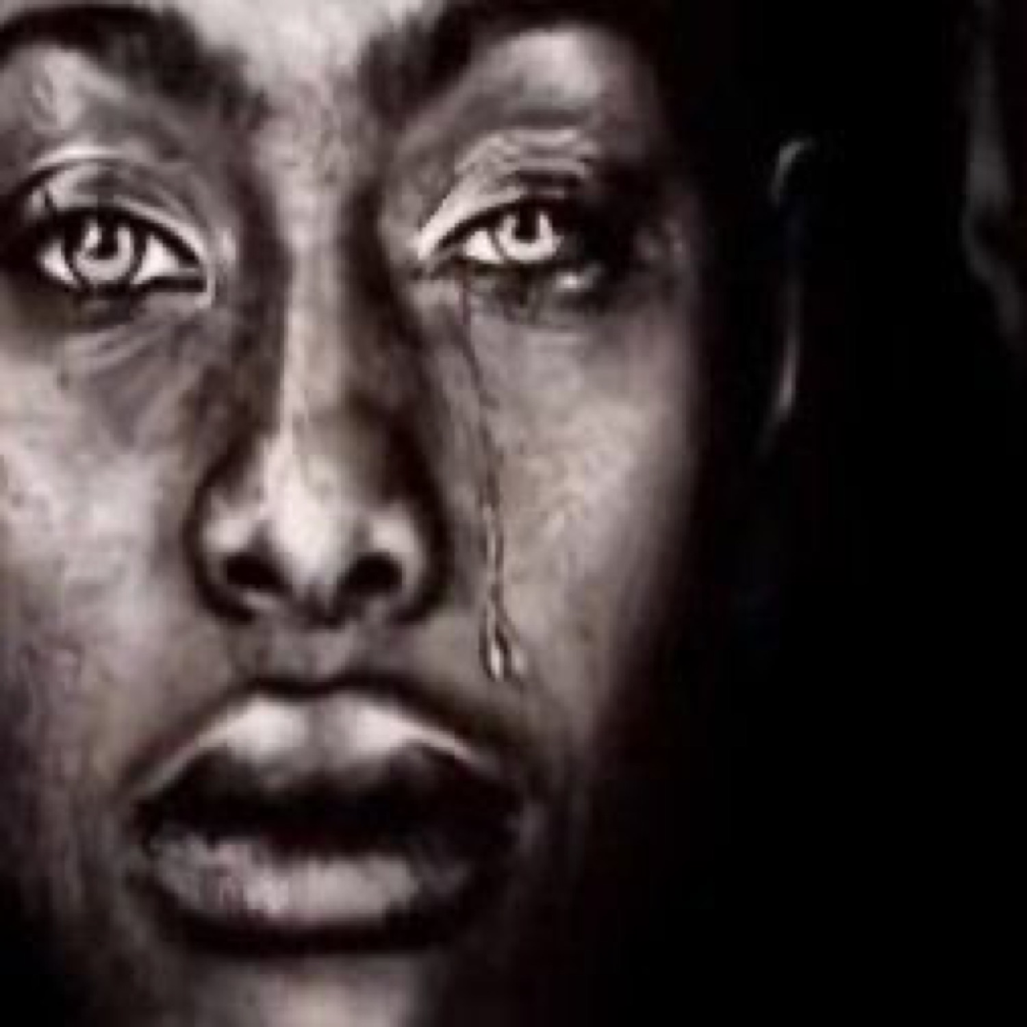 Black and white close-up of a person crying with a single tear running down their cheek