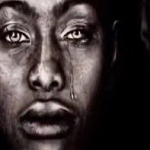 Black and white close-up of a person crying with a single tear running down their cheek