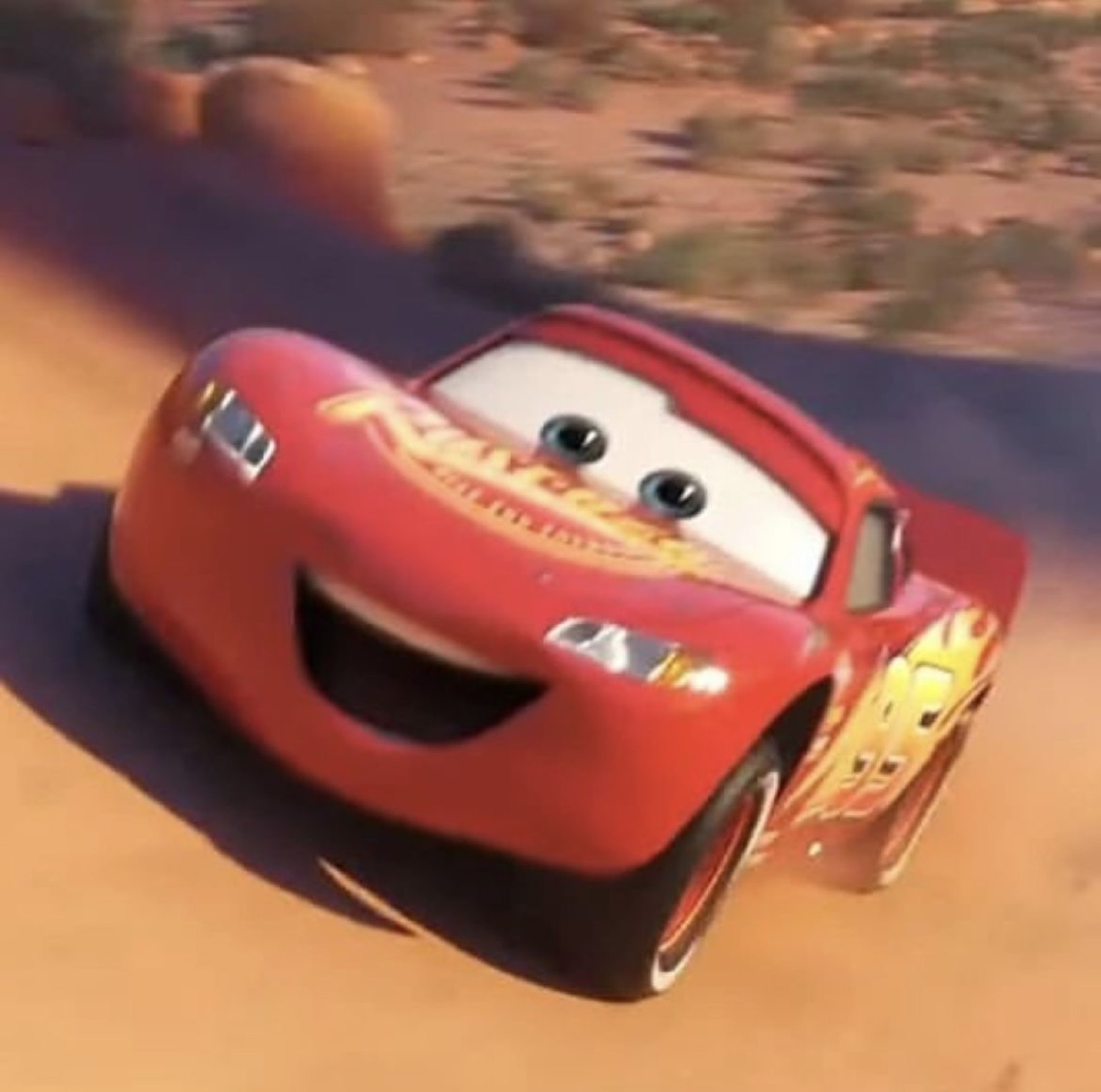 McQueen grinning as he drifts on a dirt road