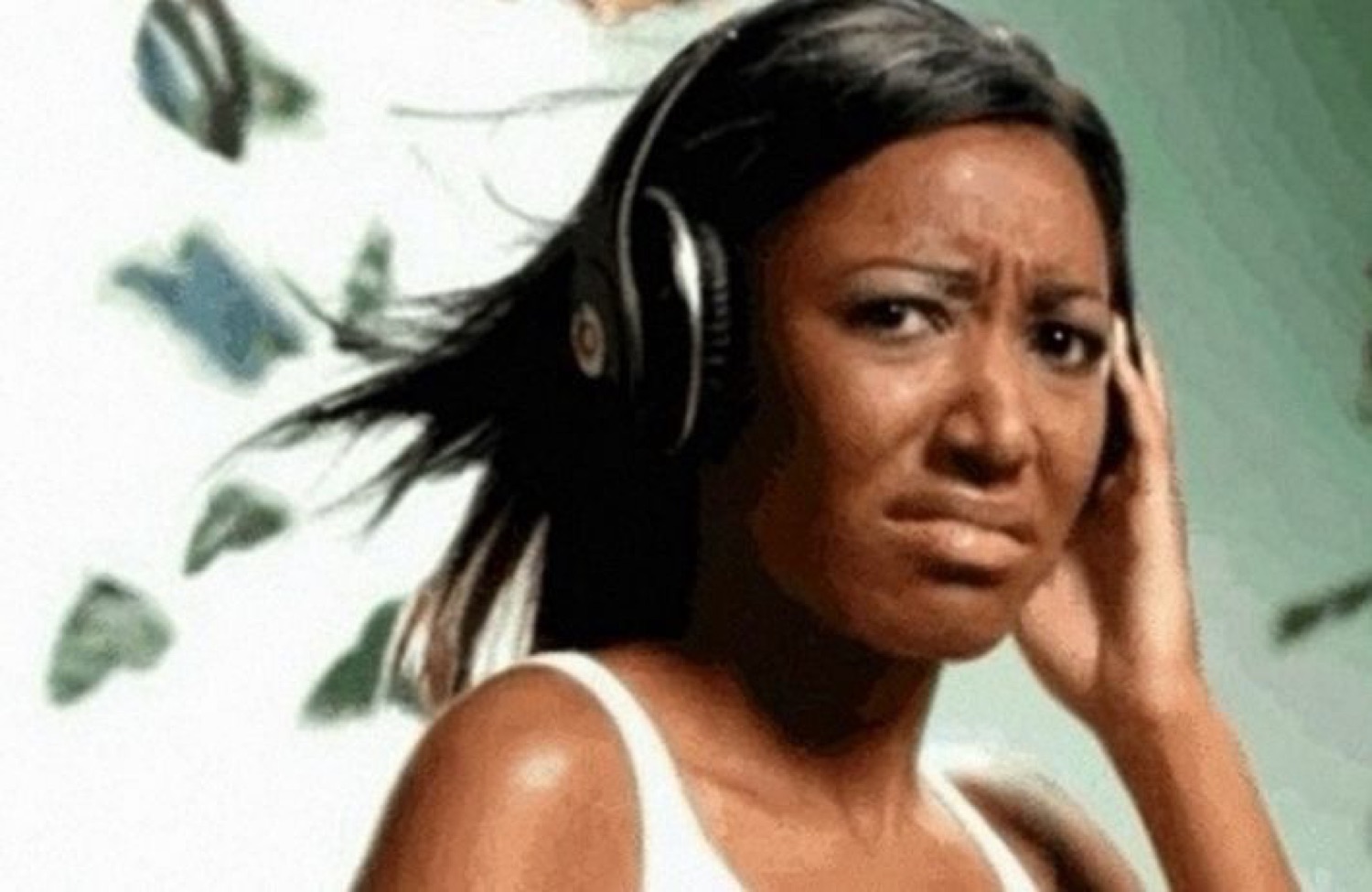 Woman in headphones squinting with a grossed-out, confused frown