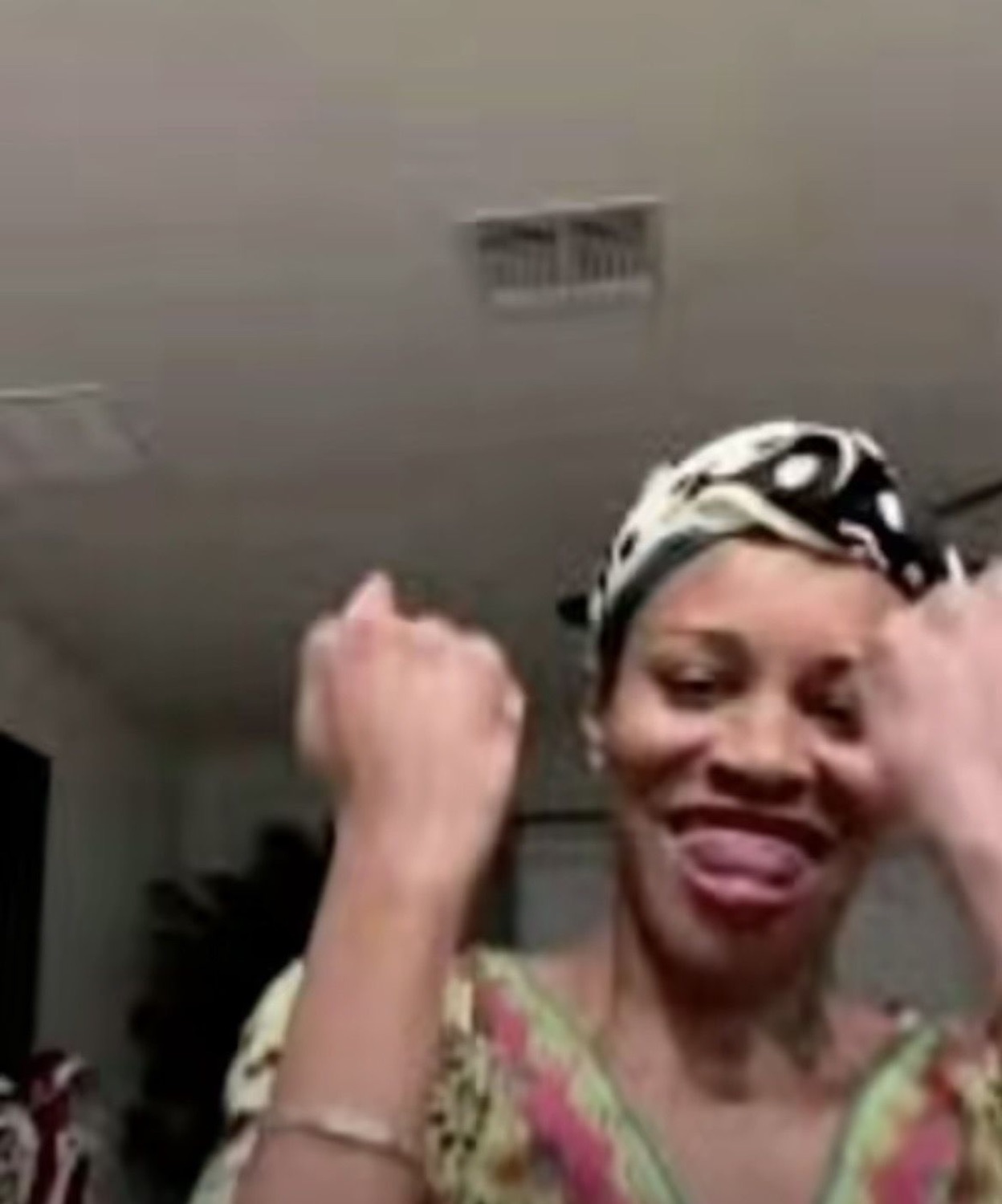 Woman in a headwrap dancing with fists raised and big grin, pure joy