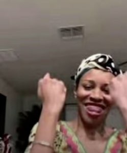 Woman in a headwrap dancing with fists raised and big grin, pure joy