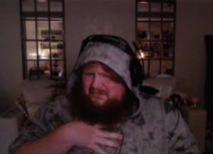 Bearded man in a hoodie and headphones squinting with a disgusted, unimpressed scowl
