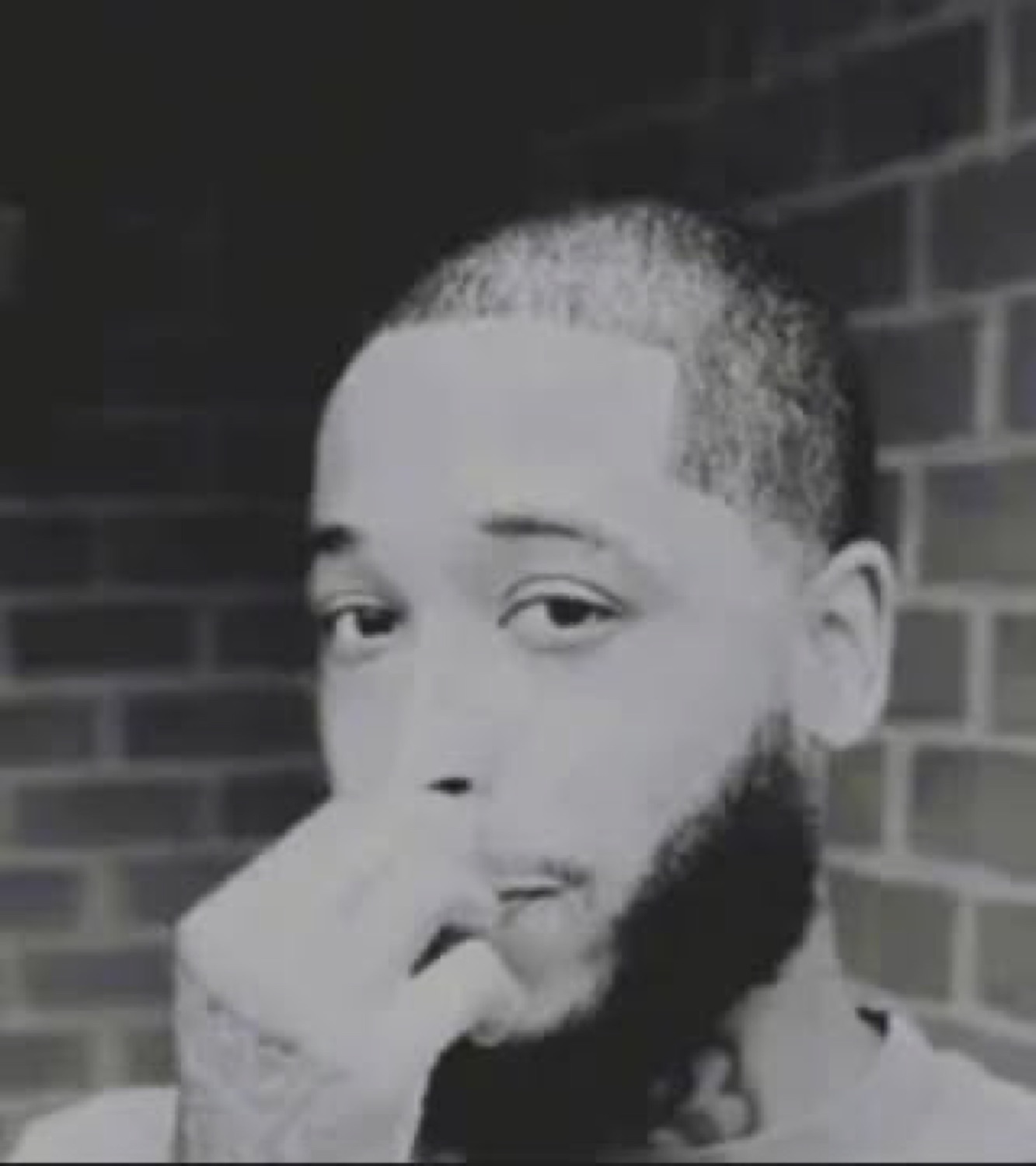 Man in black and white resting his hand on his chin with a skeptical side glance