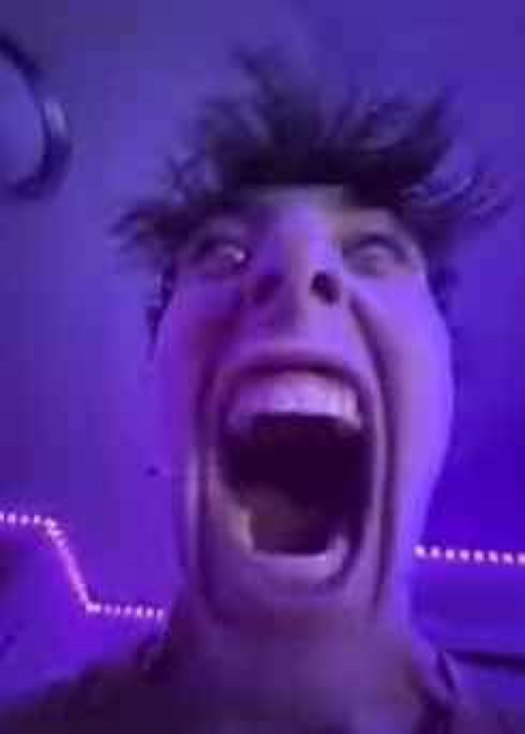 Man with wild hair screaming with his mouth wide open in purple lighting