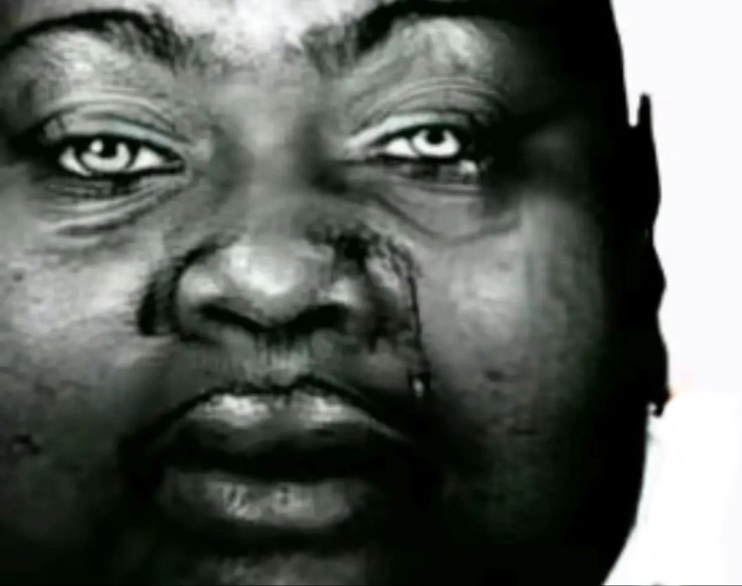Close-up of a man's face in black and white with tears streaming down his cheek