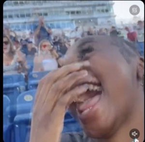 Woman in a crowd doubled over laughing with a hand covering her face