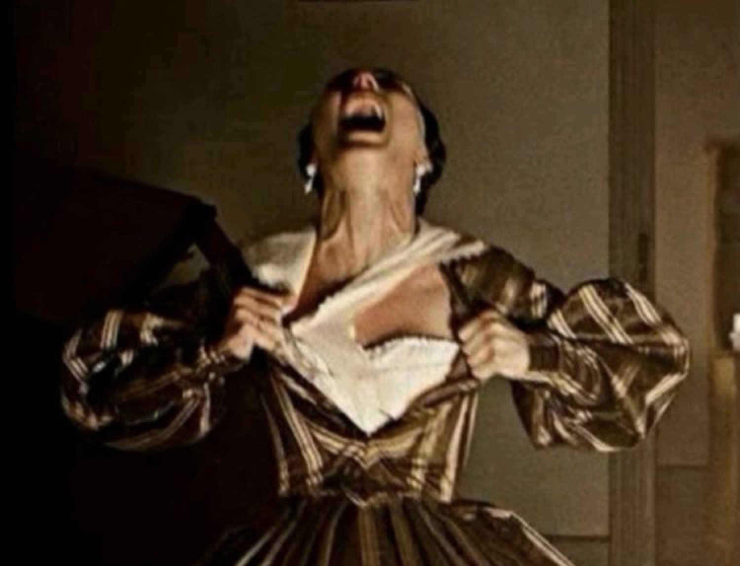 Woman in a striped ballgown ripping her shirt open and screaming to the sky dramatically
