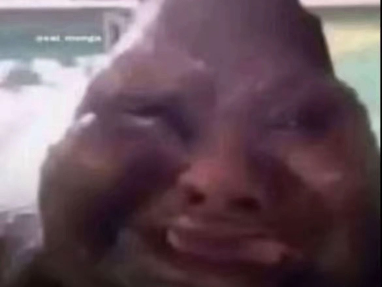Man crying up close on a video call, face streaked with tears and eyes squeezed shut