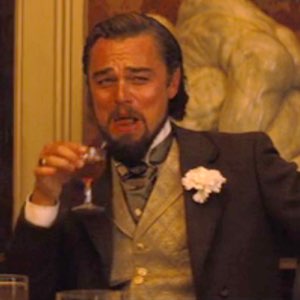 Leonardo DiCaprio in Django laughing while holding a drink in the classic mocking-laugh meme