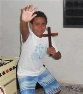 Kid holding a wooden cross and waving with a big grin, pure chaotic energy
