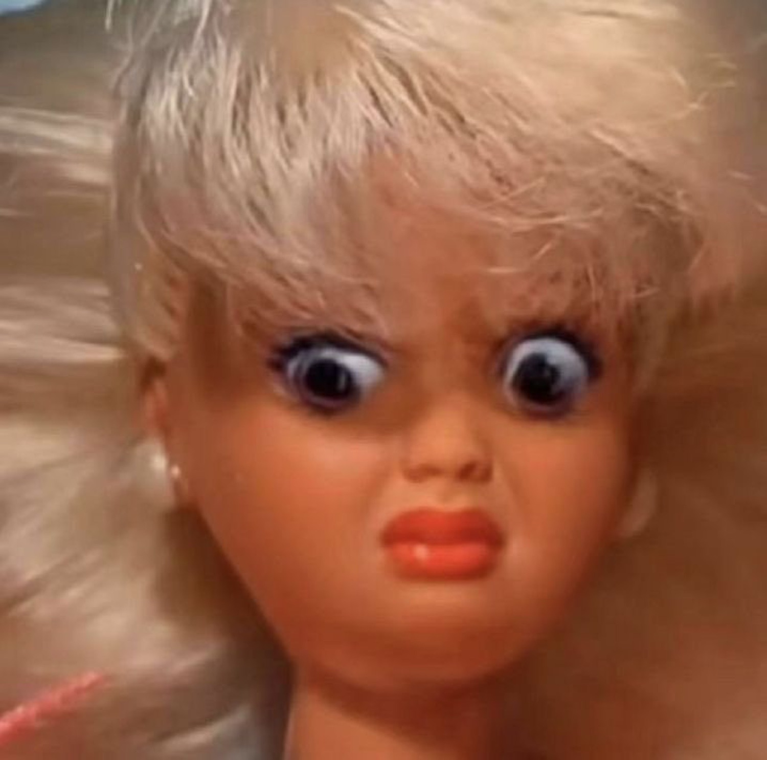 Blonde doll with bulging eyes and a curled lip pulling a horrified, disgusted grimace