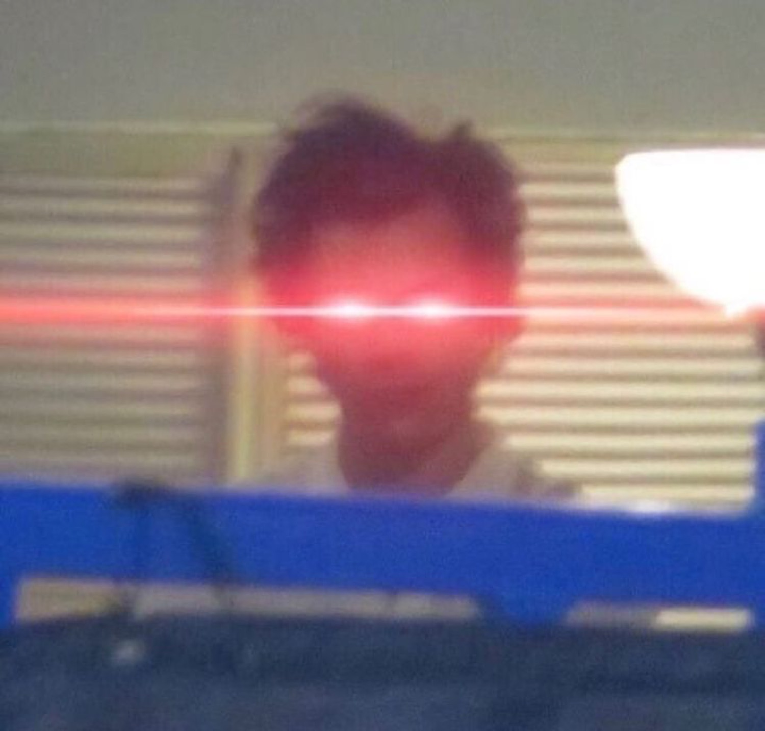 Blurry person with glowing red laser eyes sitting in a dark room