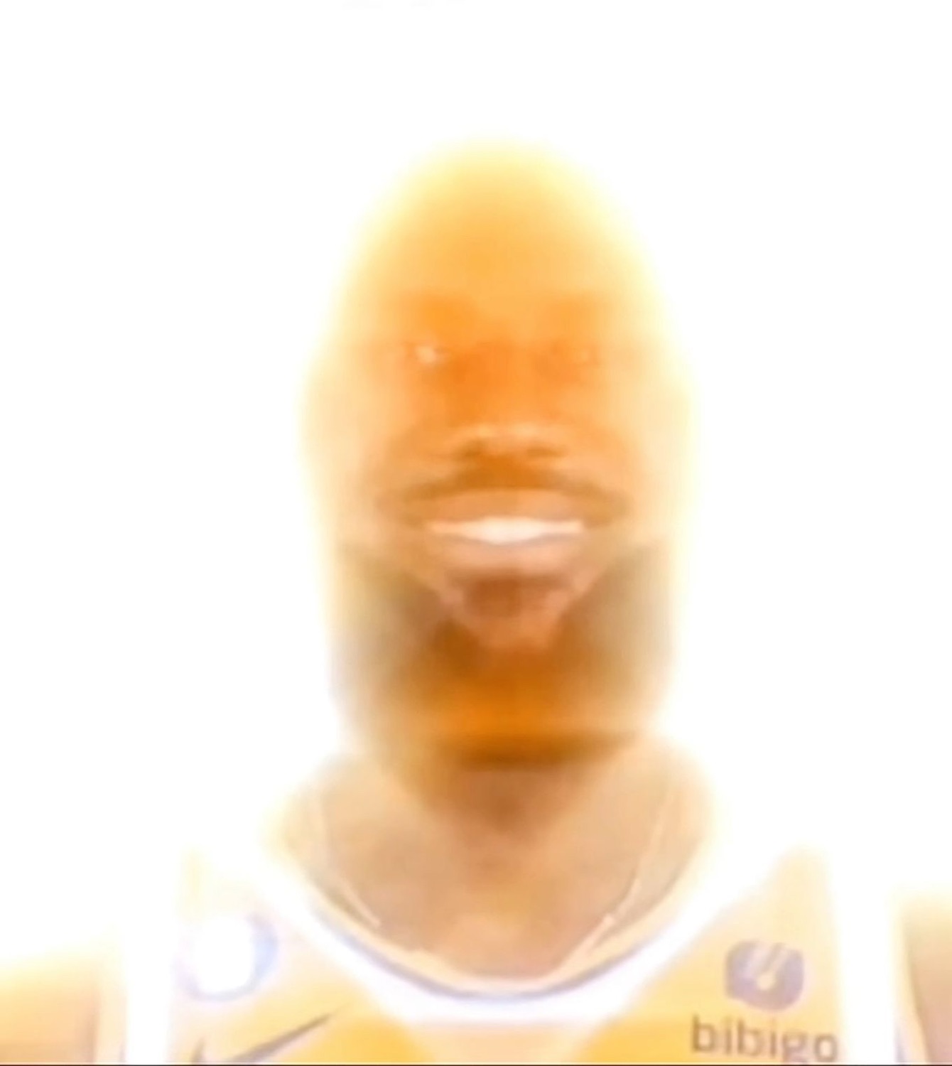 Basketball player's face blown out to a blinding orange glow while grinning