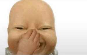 Baby scrunching up and covering their nose while stifling a laugh