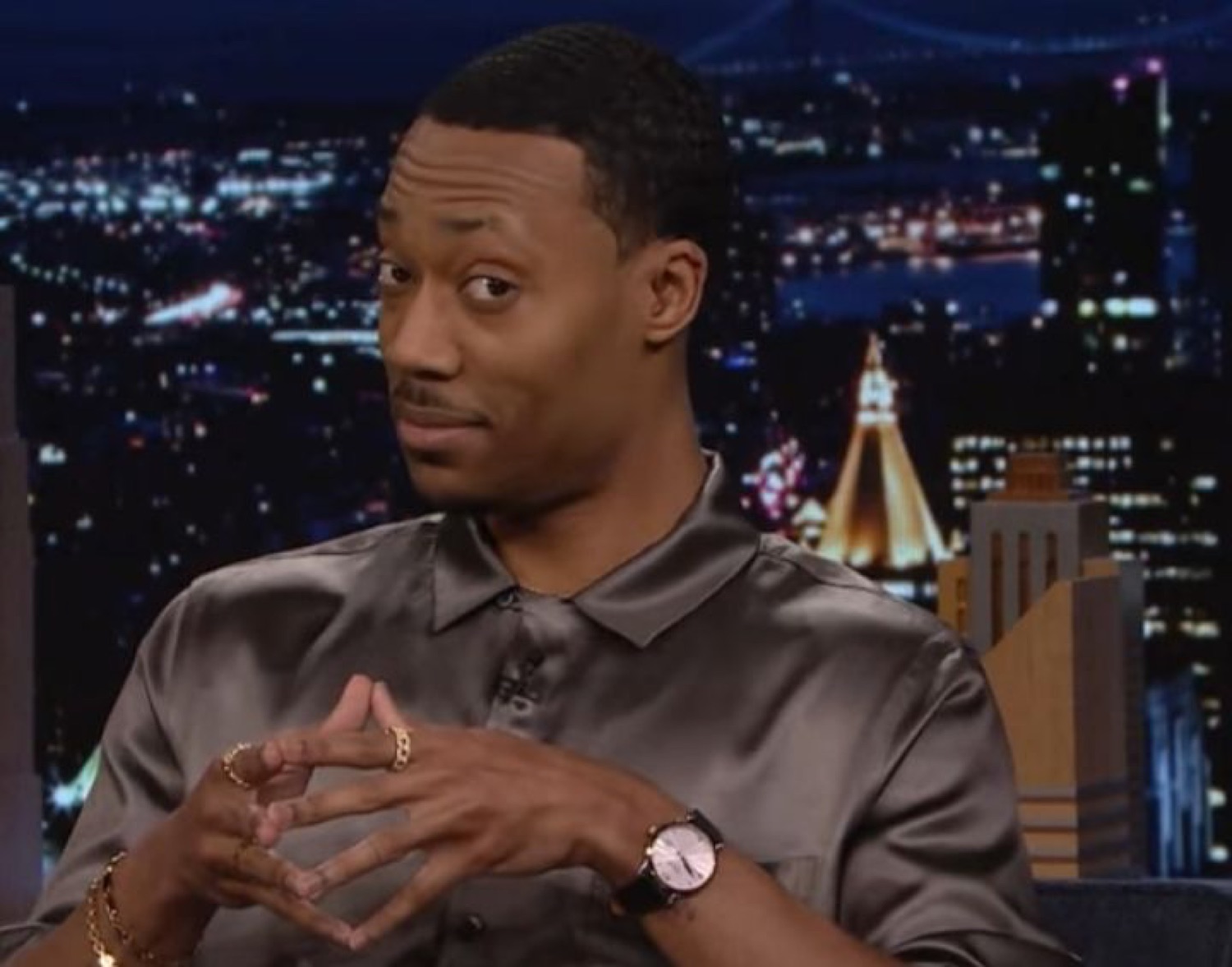 Talk show guest mid-sentence, throwing a skeptical side-eye at the host