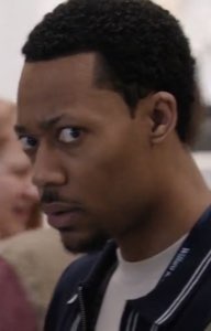 Guy in a varsity jacket cutting his eyes sideways with a baffled look