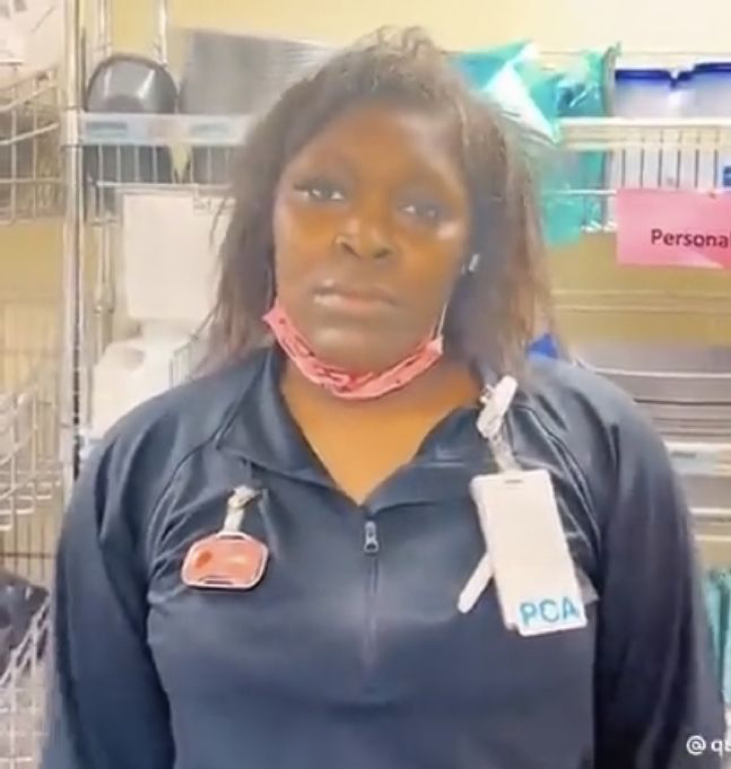 Hospital worker with mask pulled down staring blankly at the camera with zero emotion