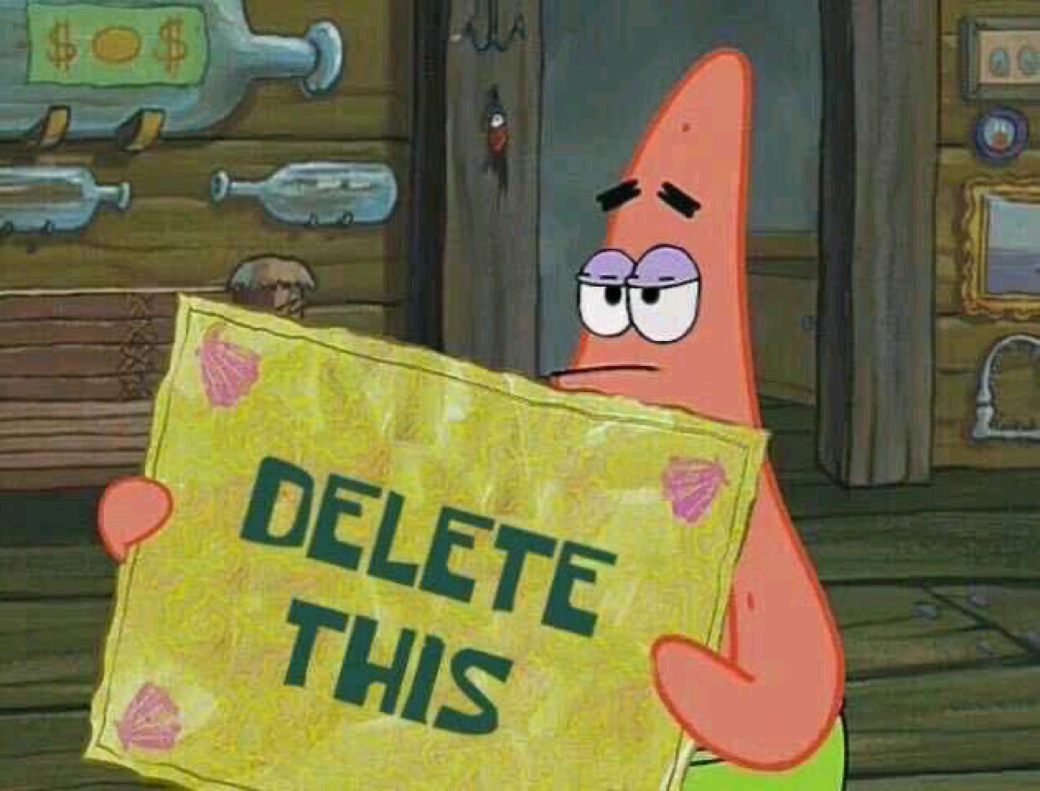 Patrick Star holding up a yellow sign that reads 'DELETE THIS'