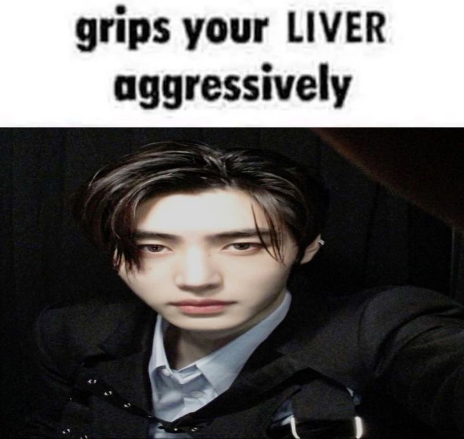 Brooding K-pop idol with intense dark stare captioned 'grips your LIVER aggressively'