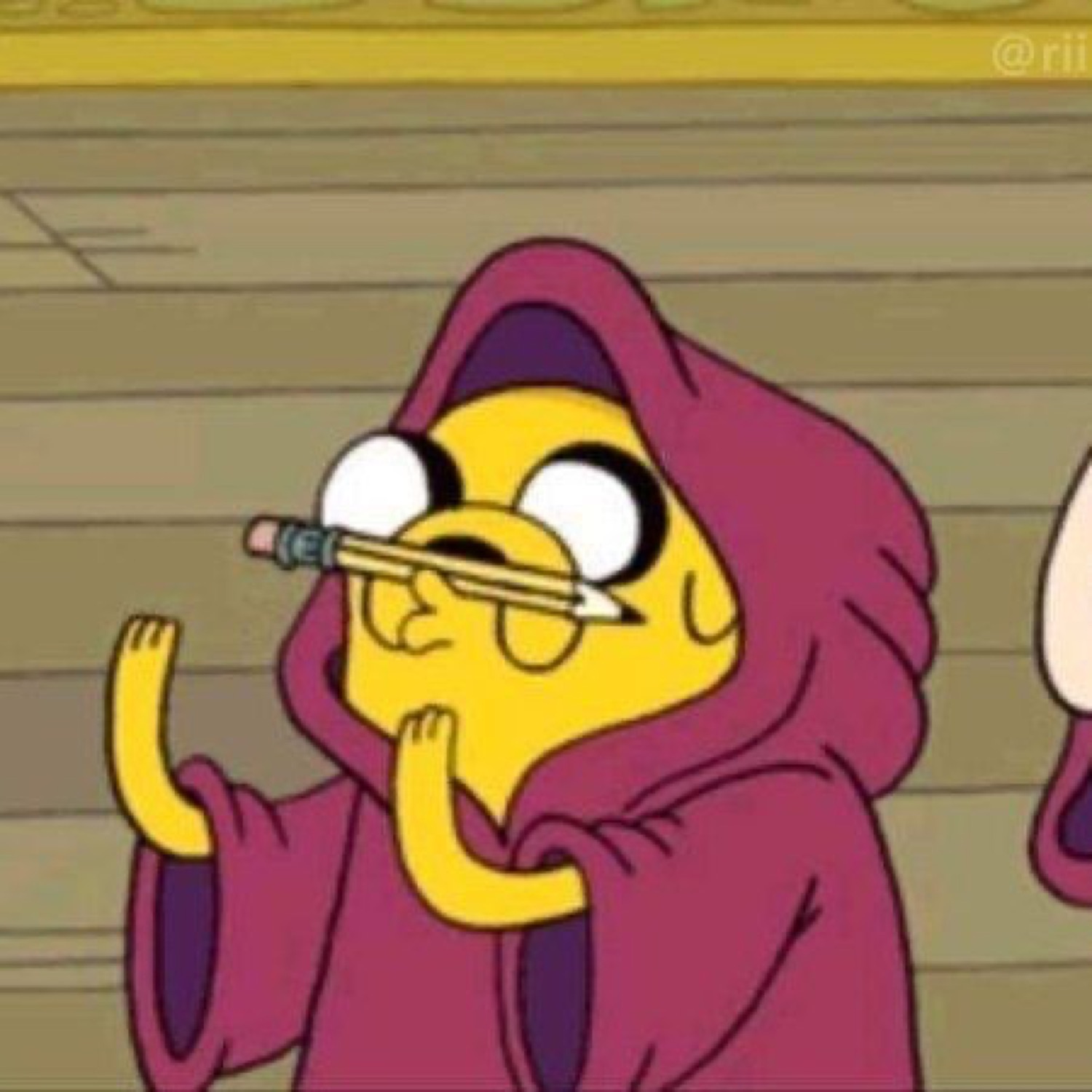 Jake from Adventure Time in a hoodie with a pencil on his face, thinking hard