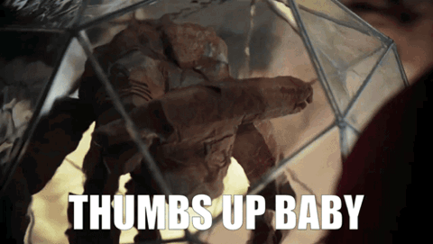Figure in a glass display case giving a thumbs up, "Thumbs up baby"