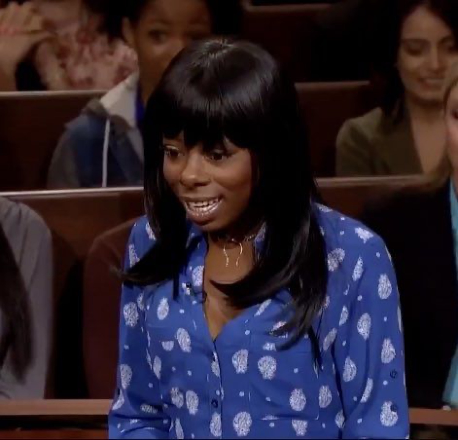 Woman in a courtroom biting her lip with a sly grin