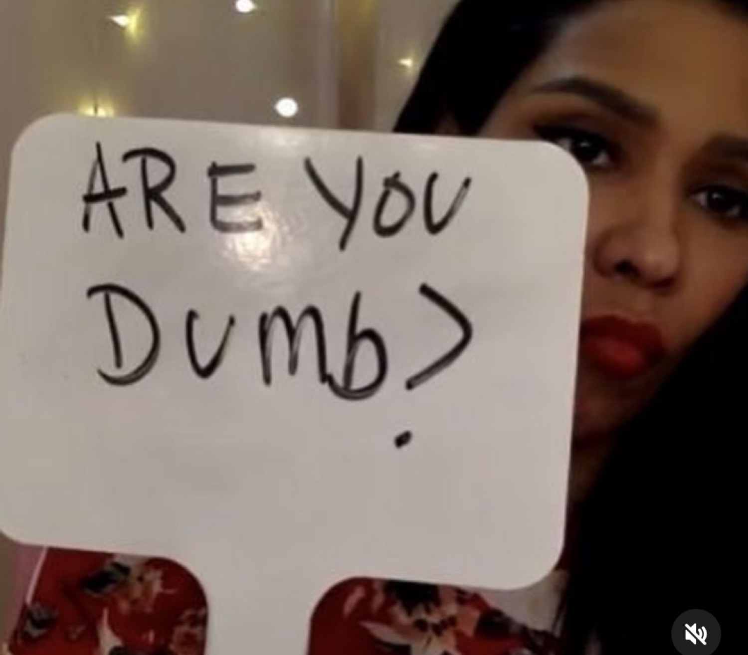 Woman holding up a whiteboard that reads 'ARE YOU DUMB?'
